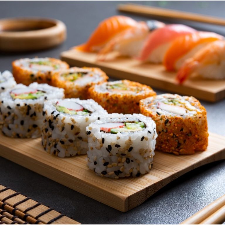 Sushi-Rollen mit Sesam und Nigiri auf einer Holzplatte.